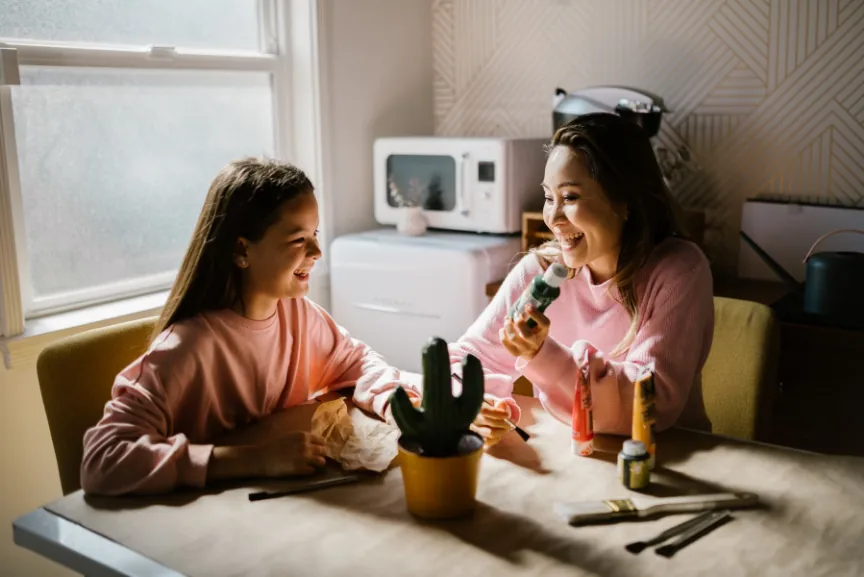 A parent and child laughing together during a creative activity